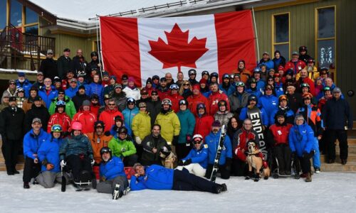 Large group of Winter Sports Clinic Participants smiling with a Canadian flag